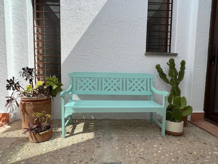Un banco verde está sentado frente a un edificio blanco.