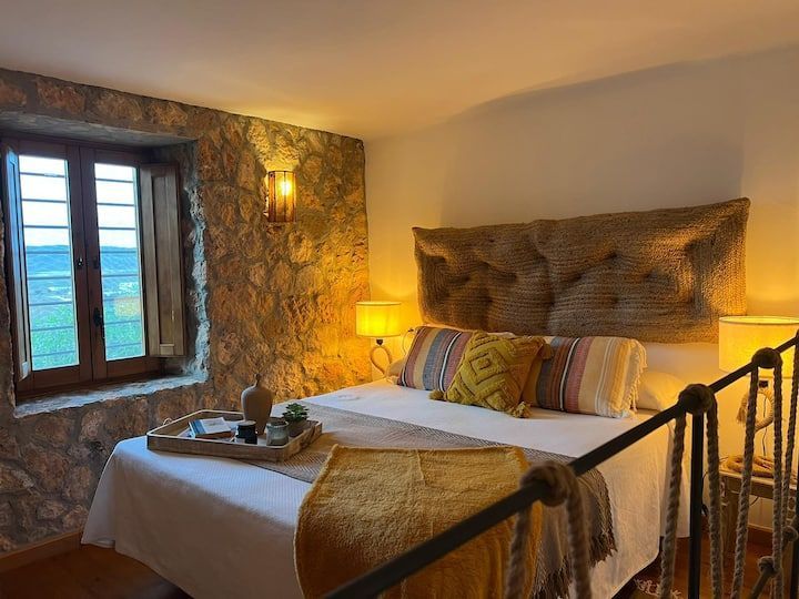 Un dormitorio con una cama, escaleras y una ventana.