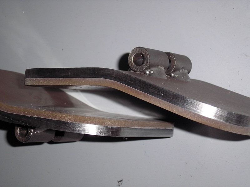 Un par de sandalias de metal están sobre una superficie blanca.