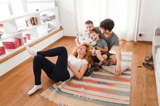 Una familia está acostada sobre una alfombra en el suelo de una sala de estar.