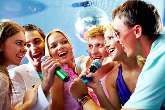 Un grupo de personas está cantando con micrófonos en una fiesta.