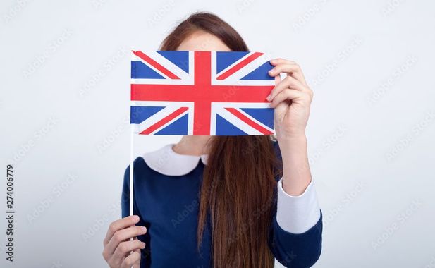 Personne tenant le drapeau du Royaume-Uni sur son visage, sur un fond blanc.