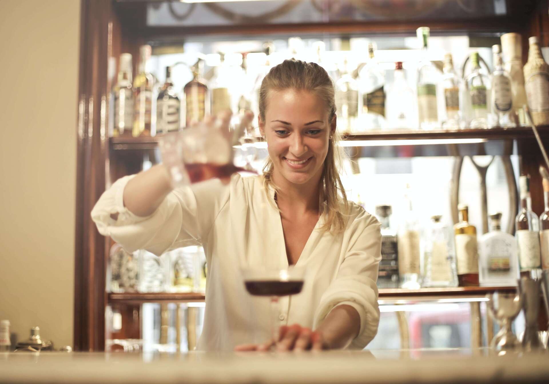 Eine Frau schenkt in einer Bar Wein in ein Glas ein.