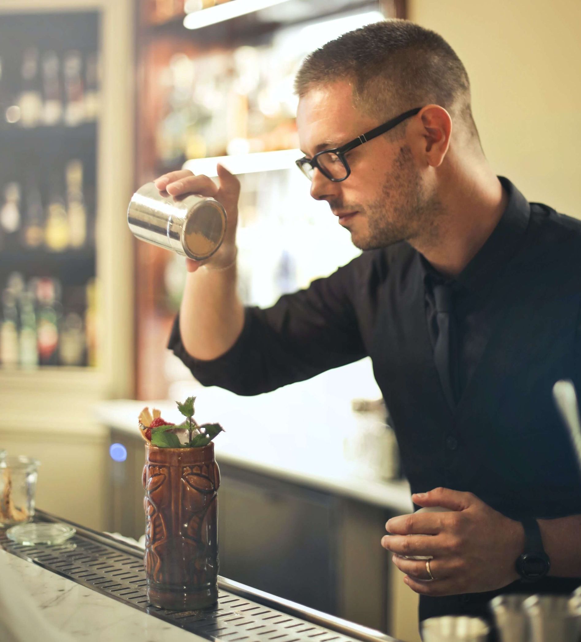 Ein Barkeeper gießt ein Getränk in eine Vase