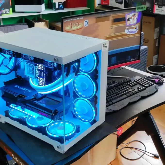 Torre de PC personalizada con iluminación azul sobre un escritorio, con monitor y teclado al fondo.