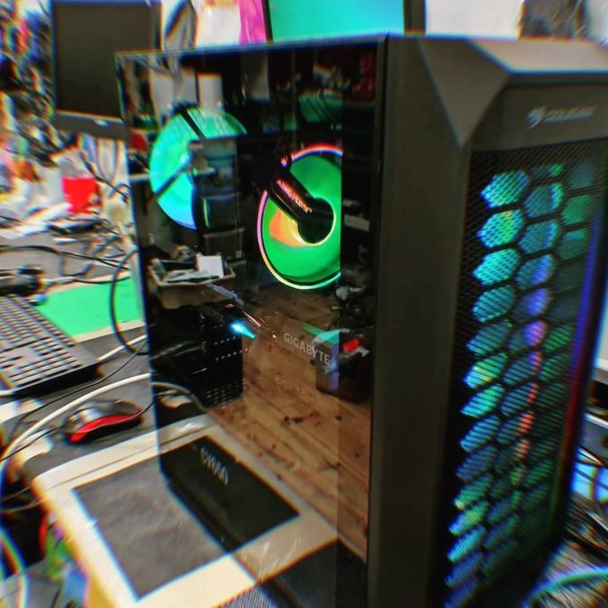 Ordenador para juegos con ventiladores iluminados con RGB sobre un escritorio desordenado, visto desde un lateral.