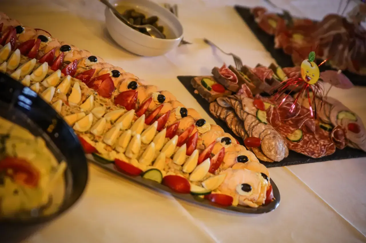 Buffet composé de plats disposés : fruits de mer, tomates, œufs, olives et charcuterie sur une nappe blanche.
