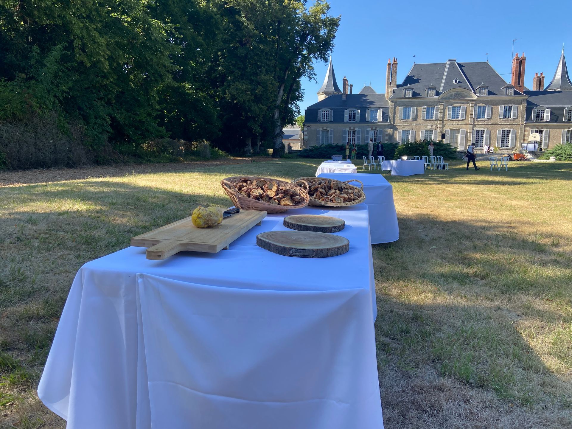 Table dressée pour un événement sur une pelouse, avec un château en arrière-plan.