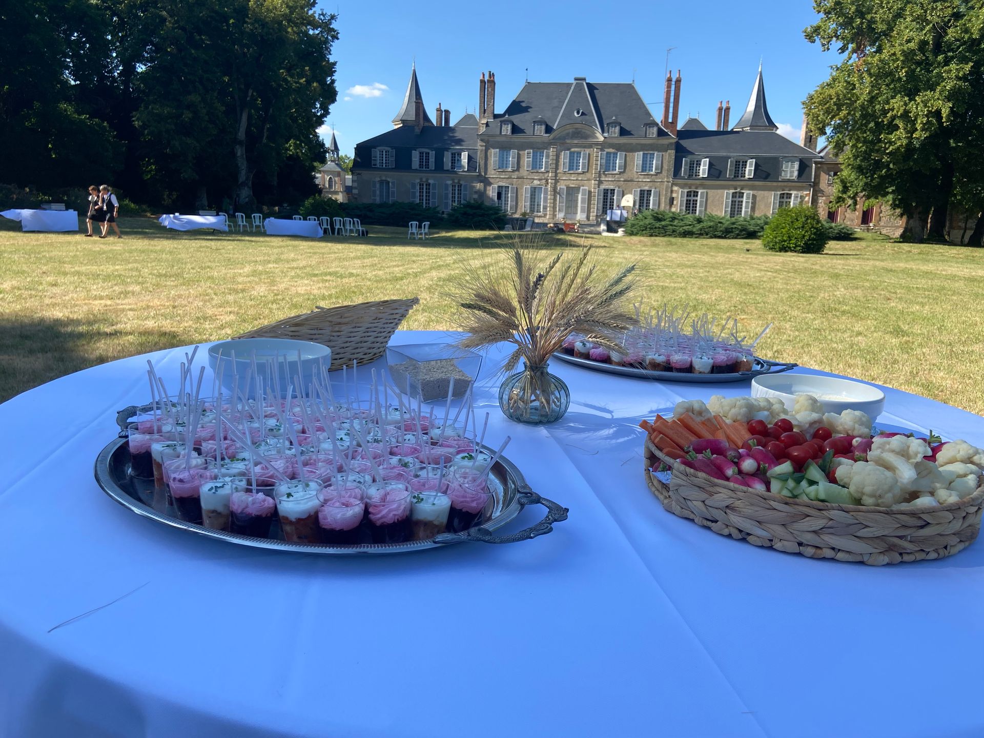 Une table garnie de mets pour un événement en plein air devant un grand château.