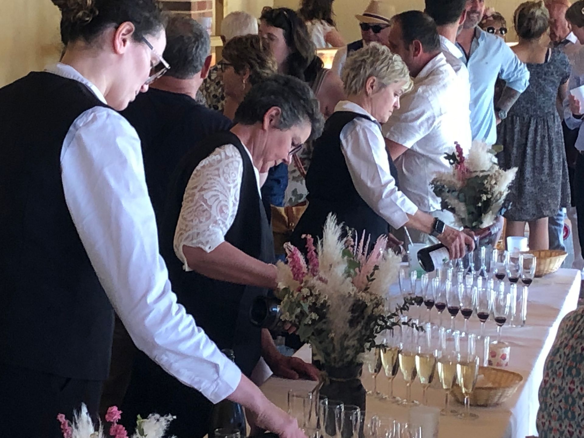 Des gens assistent à une dégustation de vins, des serveurs servent des échantillons.