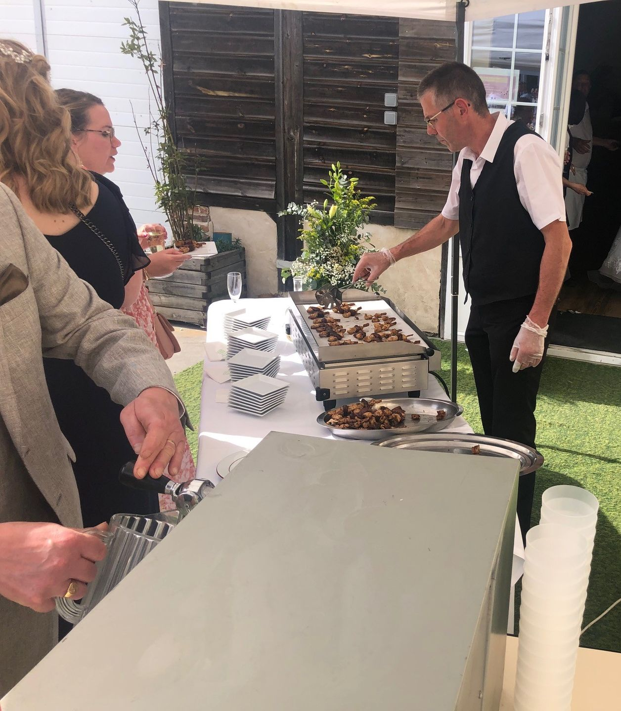 Traiteur servant des repas lors d'un événement en plein air. Les invités se tiennent près d'un buffet avec des réchauds.