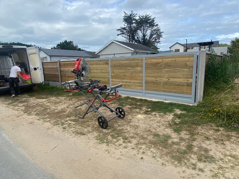 Une scie à onglets montée sur un support portatif devant une clôture.