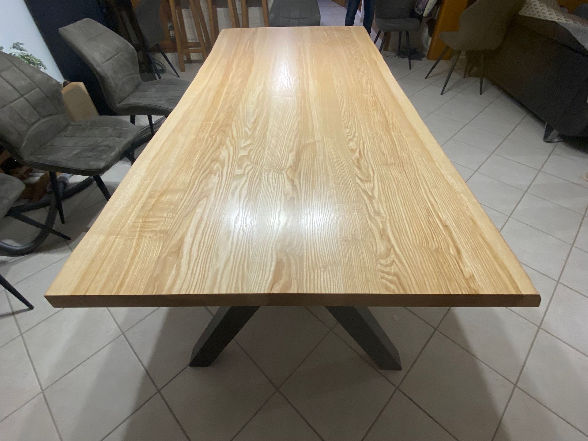 Une table à manger en bois clair avec un piètement en métal foncé en forme de X.