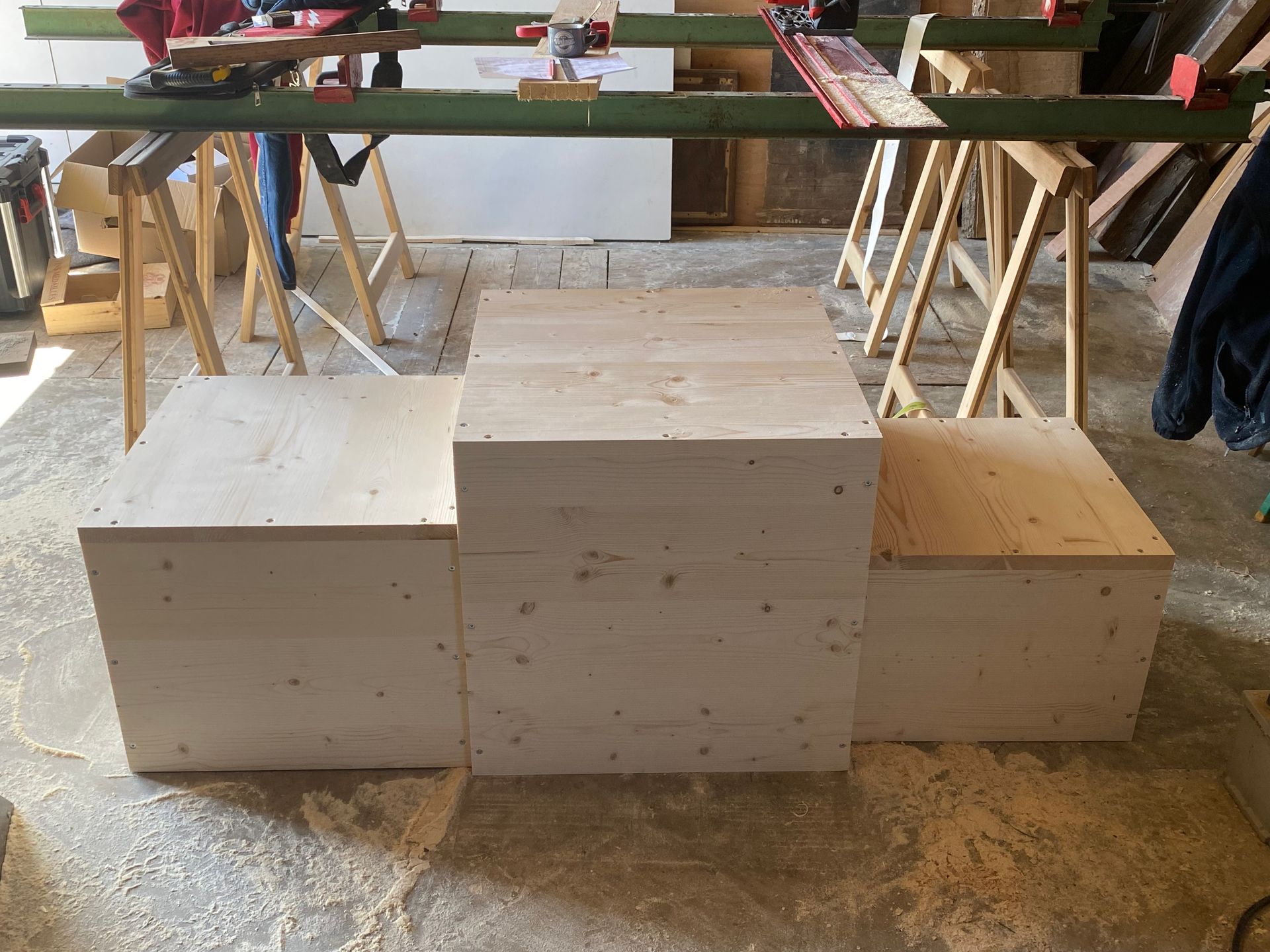 Dans un atelier de menuiserie, un podium de victoire en bois à trois niveaux.