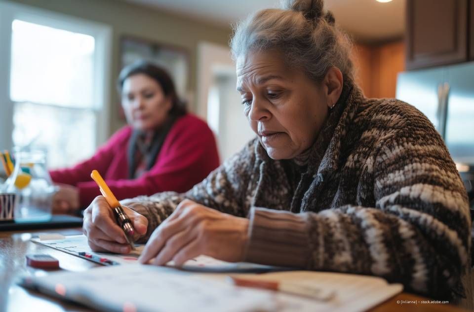 Person mit Gebärdensprache, Hände zusammen, rechte Hand tippt auf die linke. Schwarzes Hemd, neutraler Hintergrund.