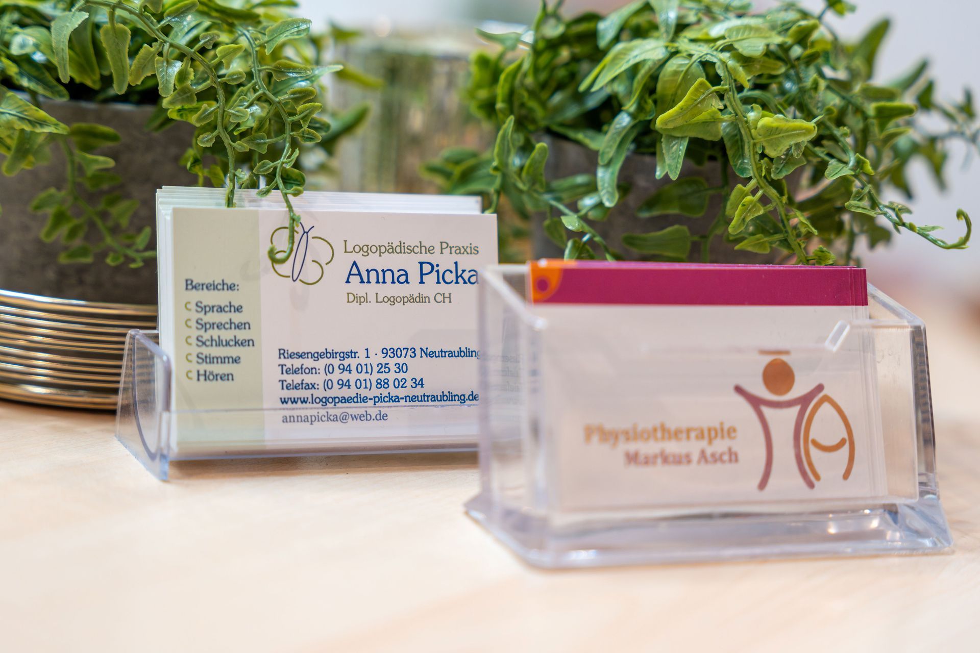 Eine Frau hält eine Karte in der Hand und schaut eine andere Person an, die ebenfalls eine Karte in der Hand hält. Die beiden befinden sich in einem Raum.