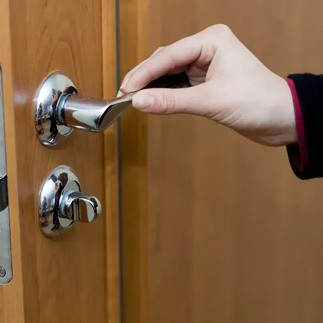 Una persona está abriendo una puerta con una manija cromada.
