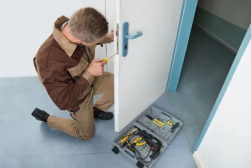 Un hombre está arreglando una cerradura de puerta con un destornillador.