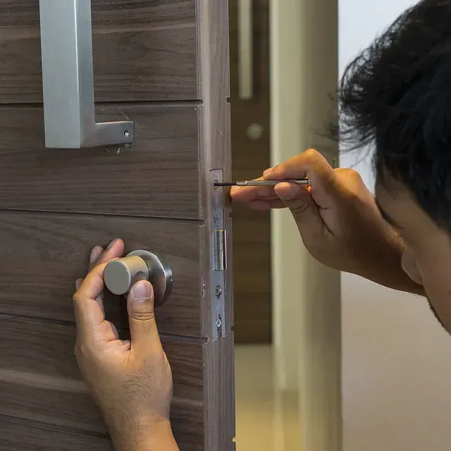 Un hombre está arreglando una puerta con un destornillador.