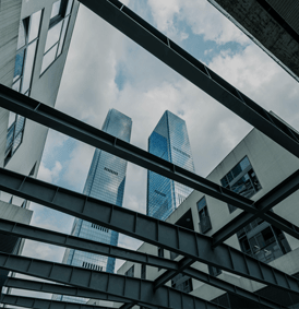 Deux gratte-ciel modernes encadrés par une structure d'acier, sous un ciel nuageux.
