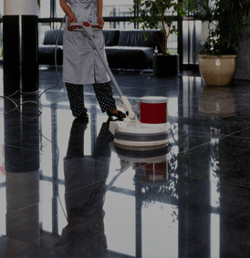 Une personne nettoie un sol noir brillant avec une polisseuse dans un bâtiment moderne.