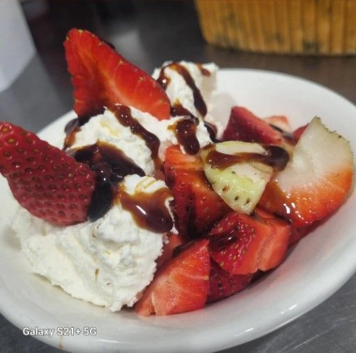 Tazón de fresas y crema batida rociada con salsa de chocolate.