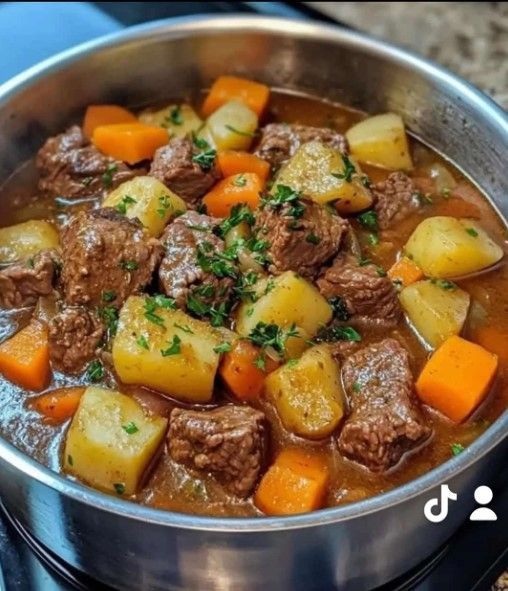 Guiso de ternera con patatas y zanahorias en olla, adornado con perejil.