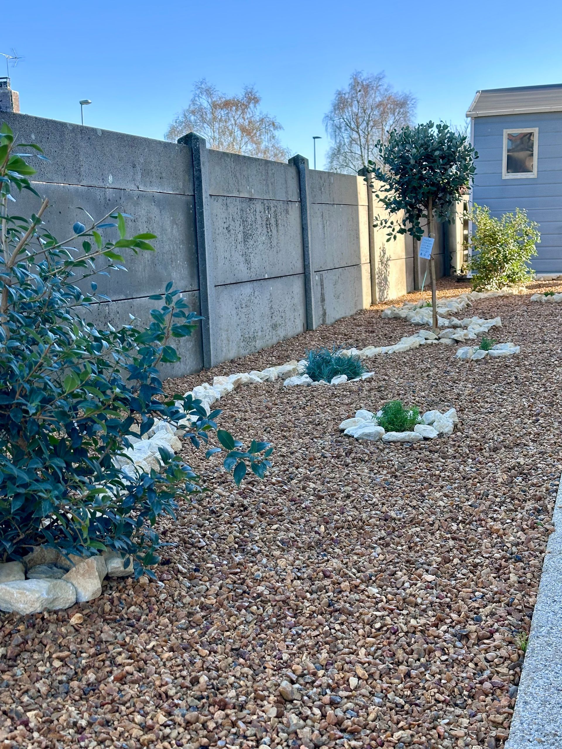 Maison bleue avec porche blanc et jardin avec fleurs et pelouse.