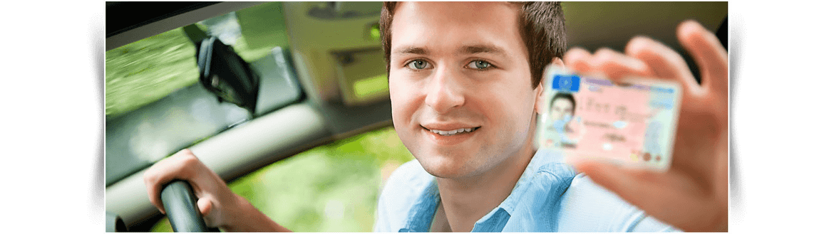 Un hombre en un coche muestra una tarjeta de crédito y sonríe a la cámara.