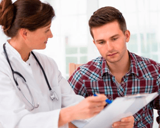 Un médico conversa sobre documentación con un paciente en un consultorio clínico bien iluminado.