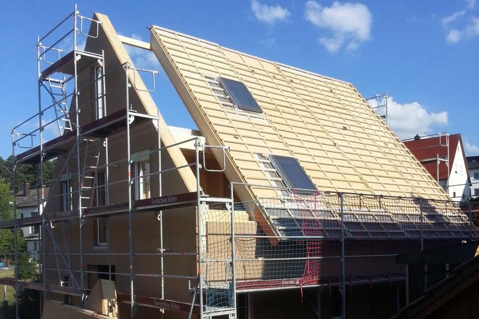 Haus im Bau, mit freiliegendem Dachstuhl und Gerüst.