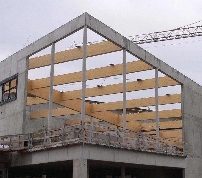 Gebäude im Bau mit Holzbalken und Betonrahmen.