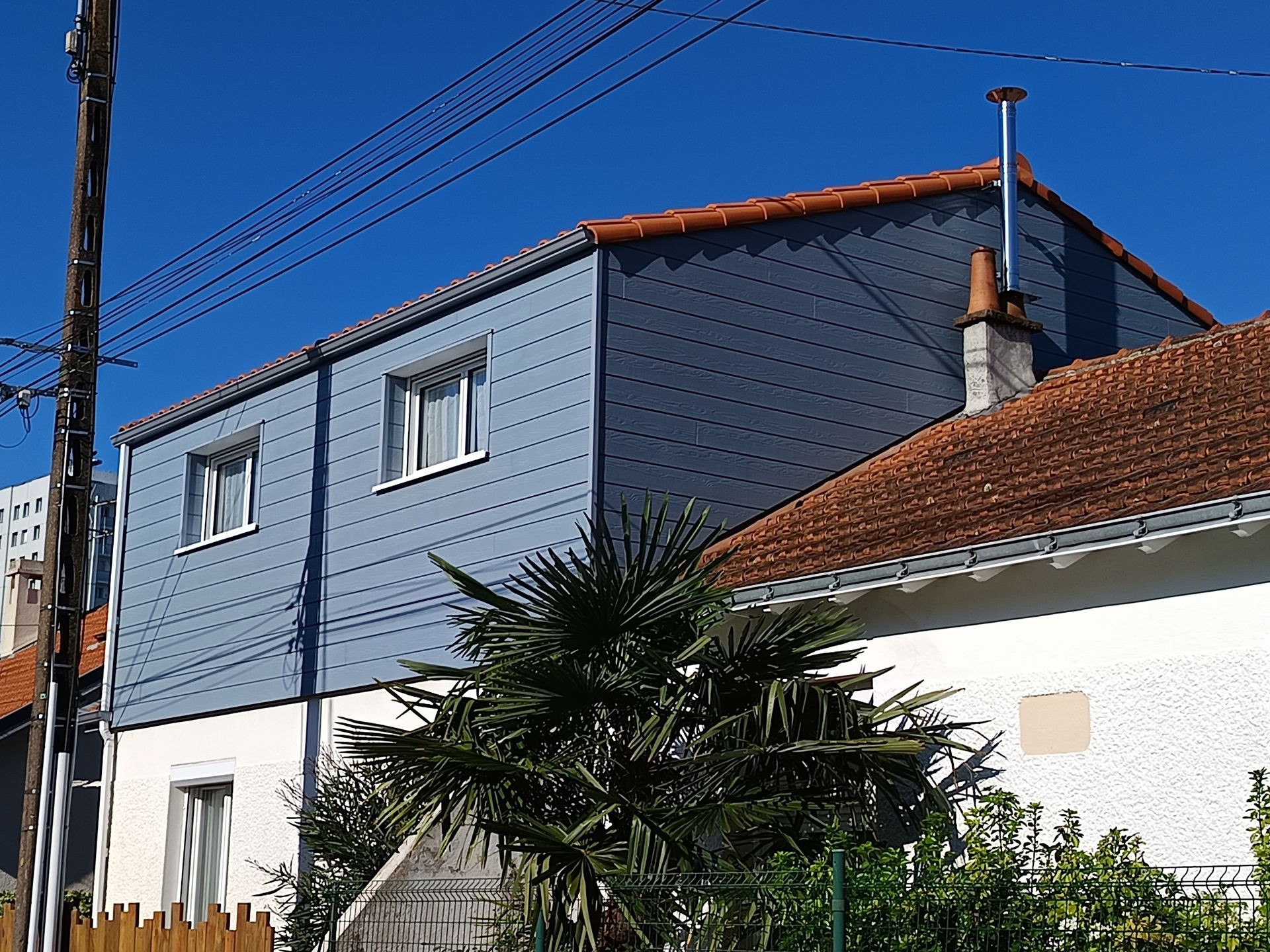 Un bâtiment résidentiel avec un bardage bleu grisé.