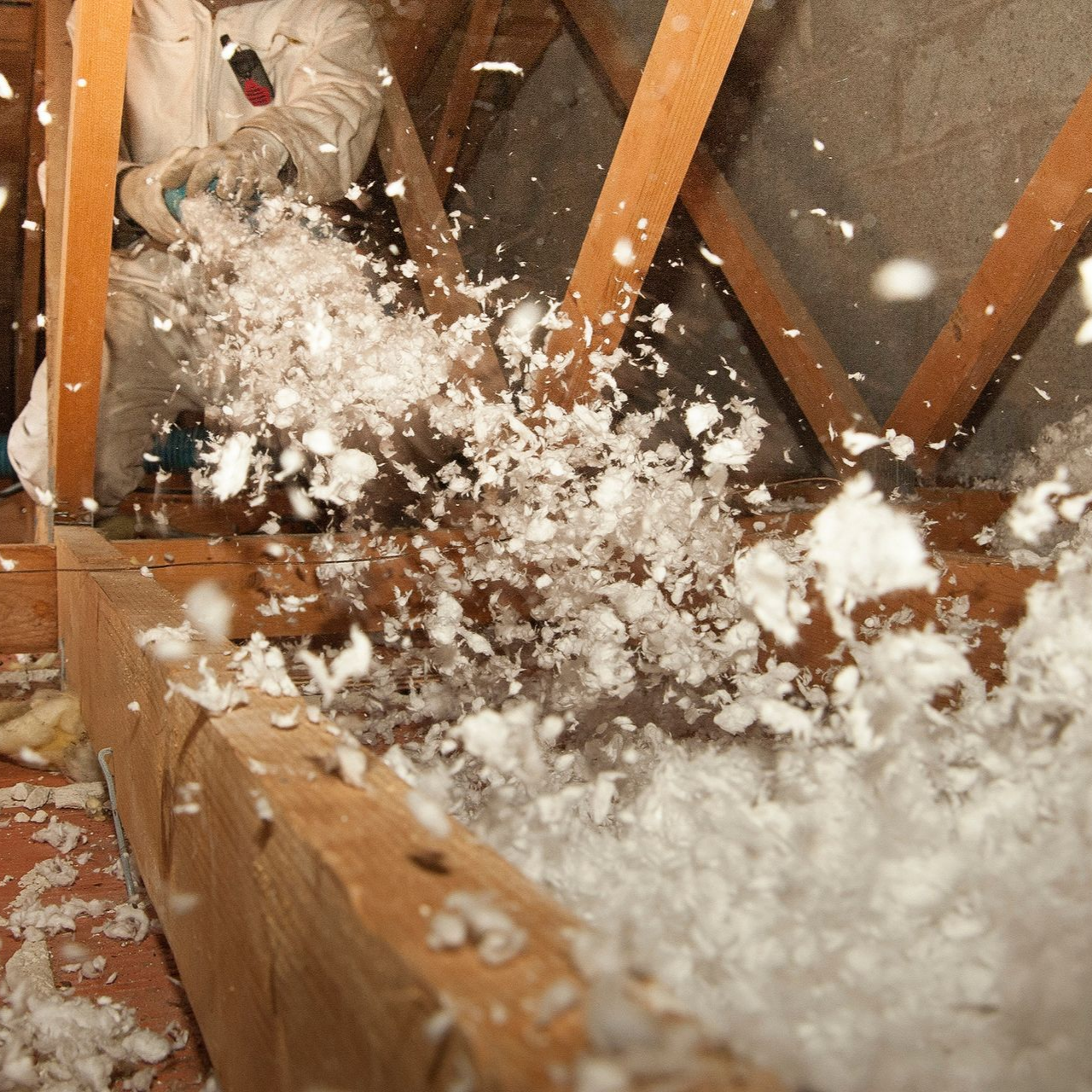 Un artisan isole des combles avec la méthode de soufflage.
