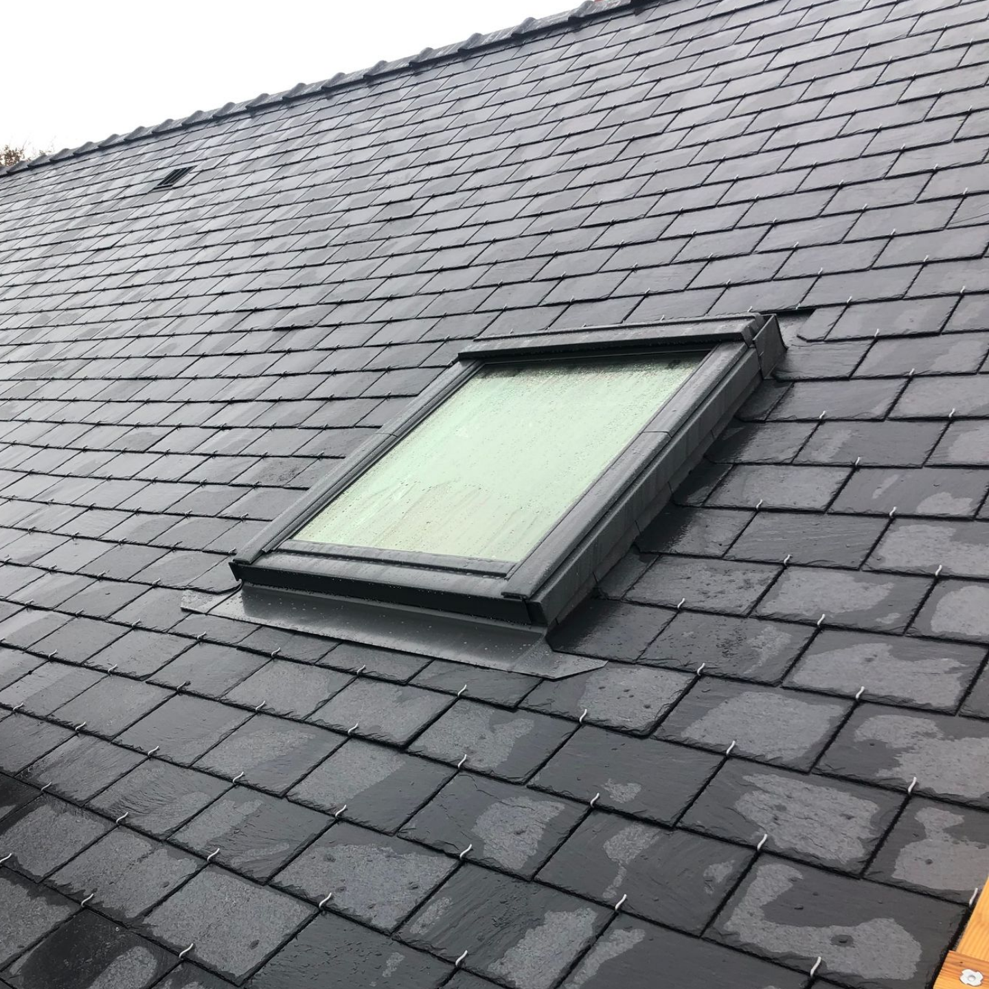 Une toiture en ardoise avec une fenêtre de toit.