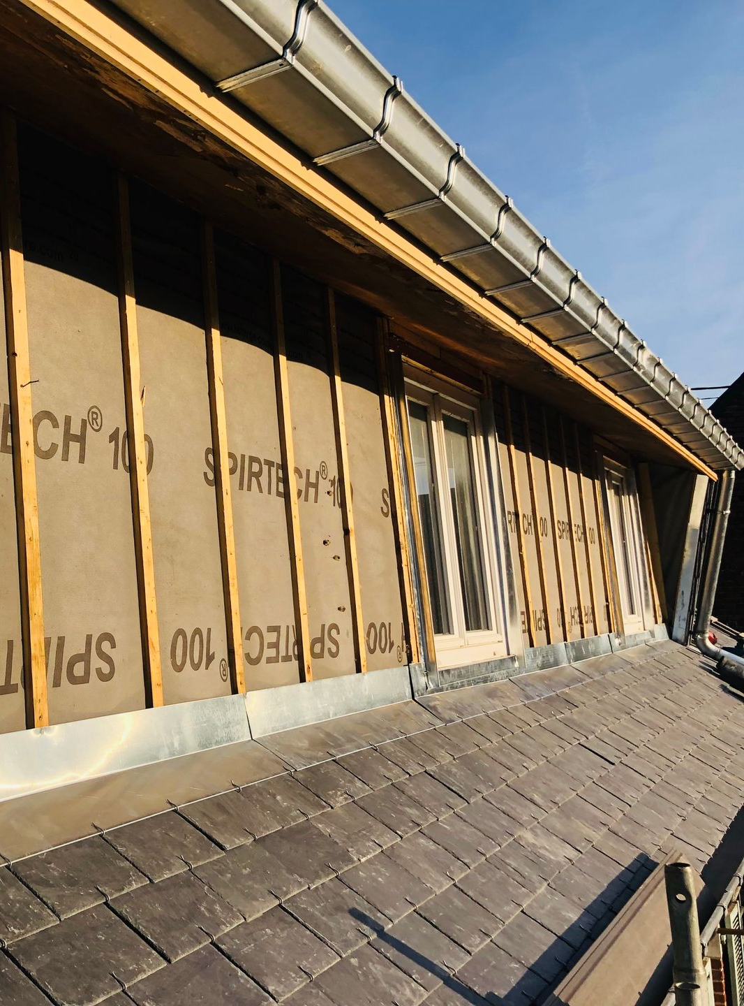 Rénovation d'un mur extérieur à ossature en bois apparente, isolation et toiture visibles.