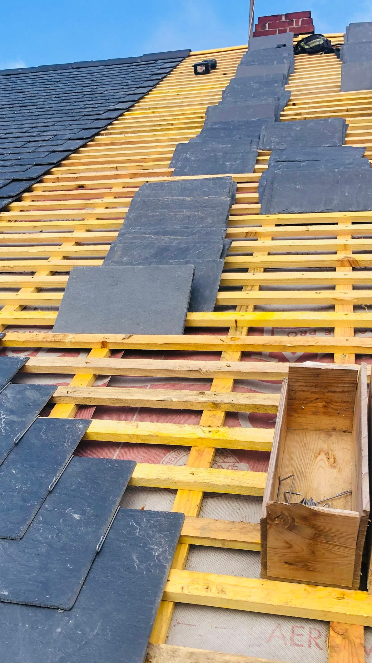 Charpente en bois et planches d'ardoise sur toiture.