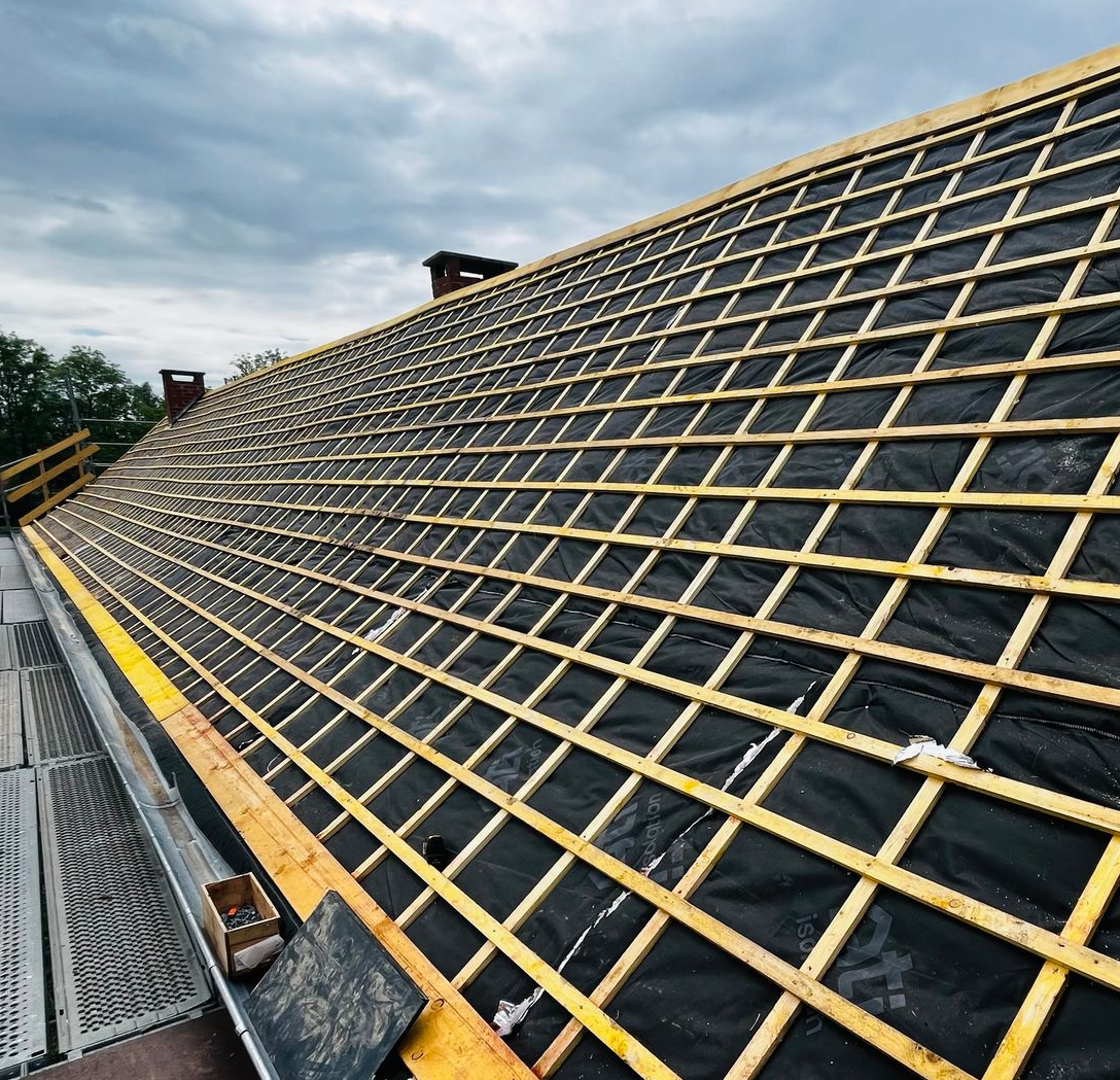 Toiture en construction avec charpente en bois et sous-couche foncée.