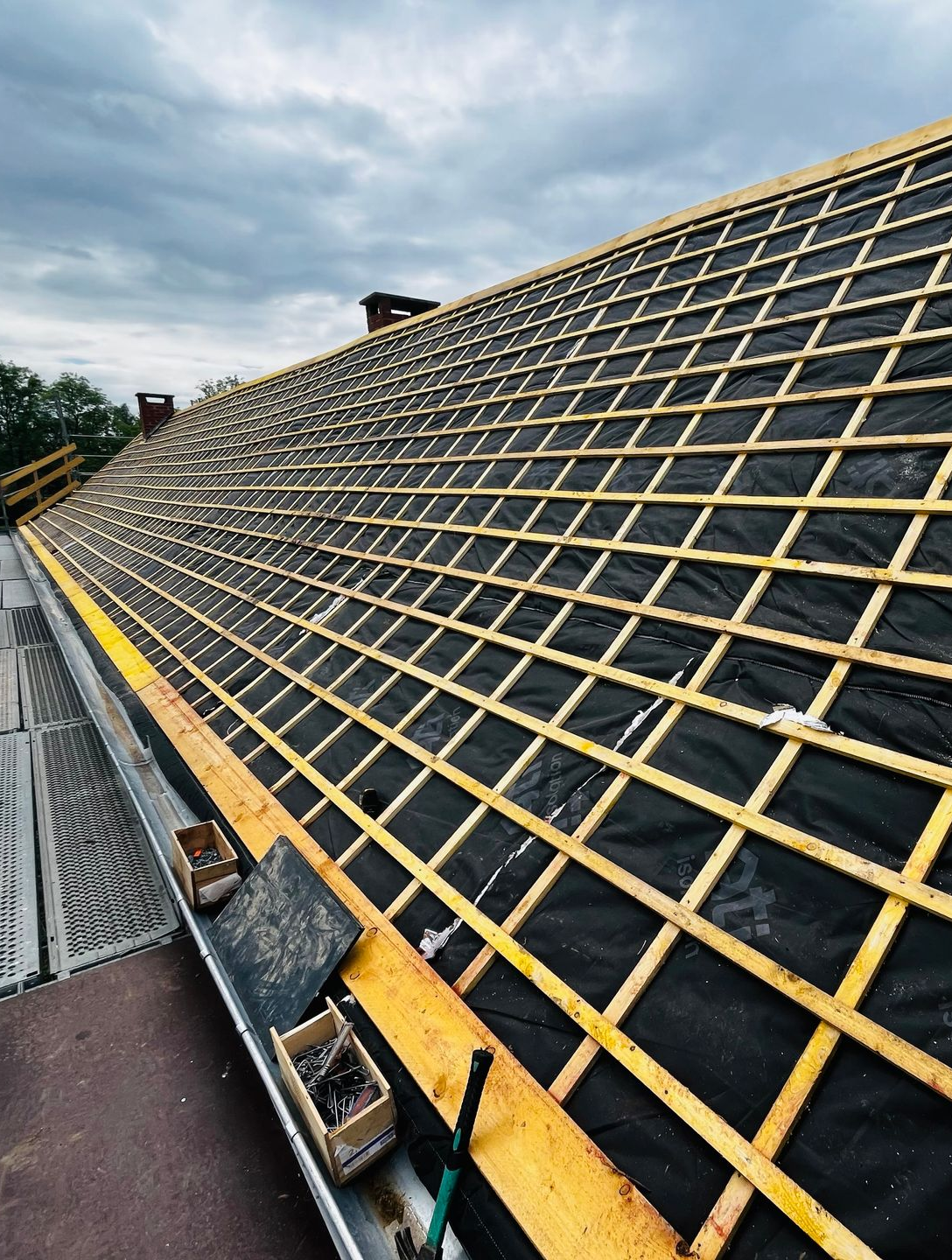 Toiture en construction avec sous-couche noire et treillis en bois.