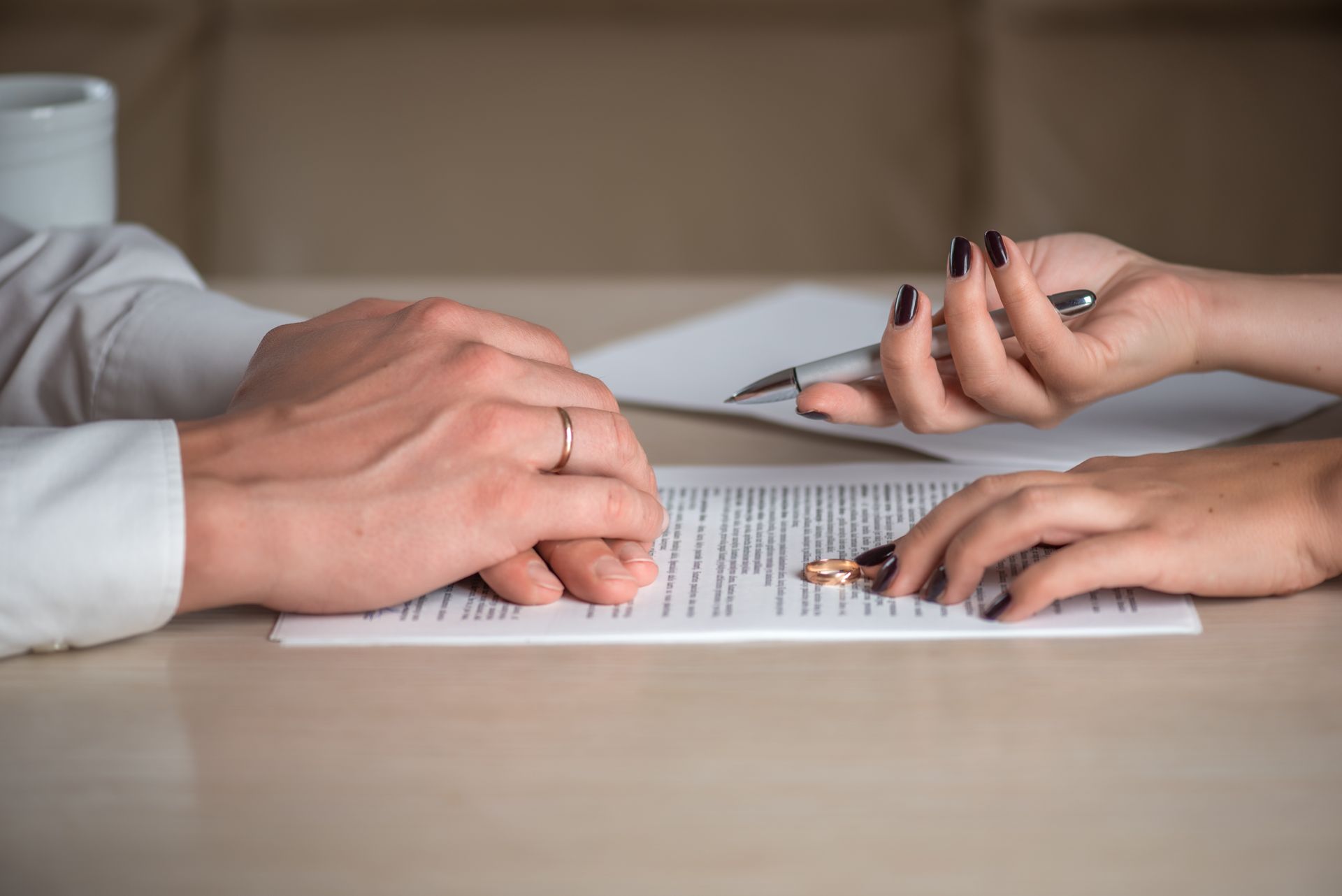 Les mains examinent et signent un document à une table avec un stylo et un bloc-notes.