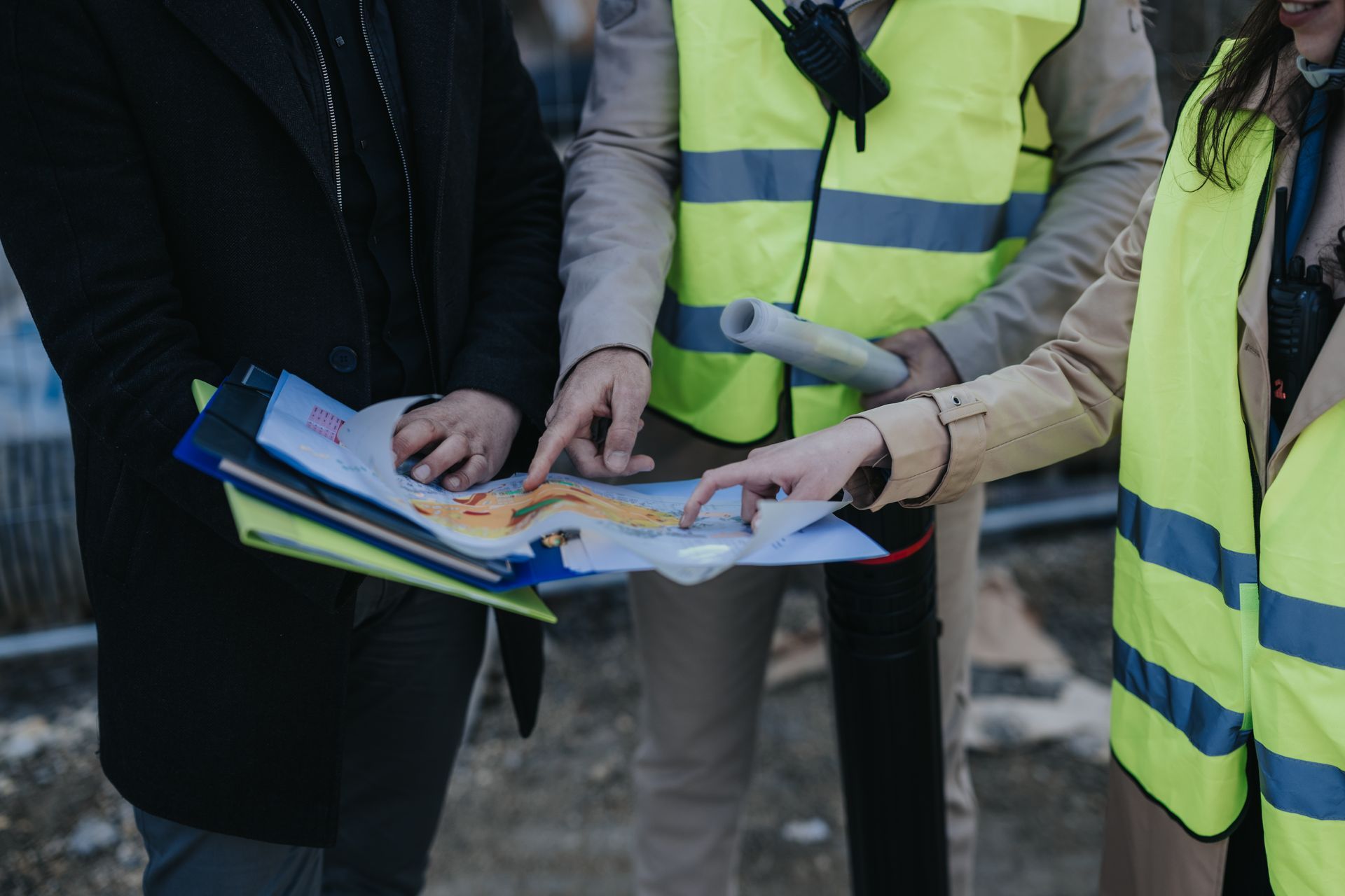 Des personnes portant des gilets de sécurité jaunes consultent une carte à l'extérieur.