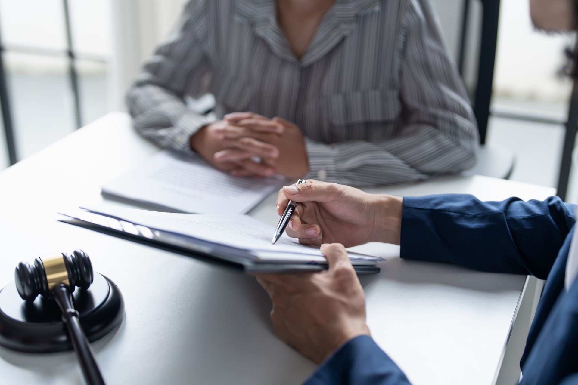 Des mains signent des documents sur un bureau lors d'une consultation juridique.