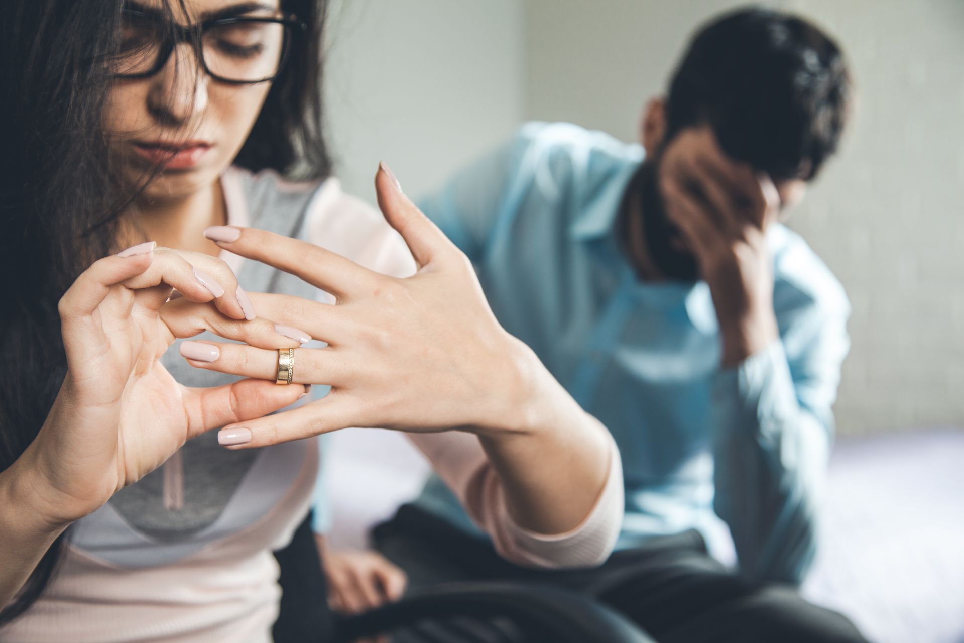 Une femme examine sa main tandis qu'un homme, à l'arrière-plan, est assis, la tête dans la main.