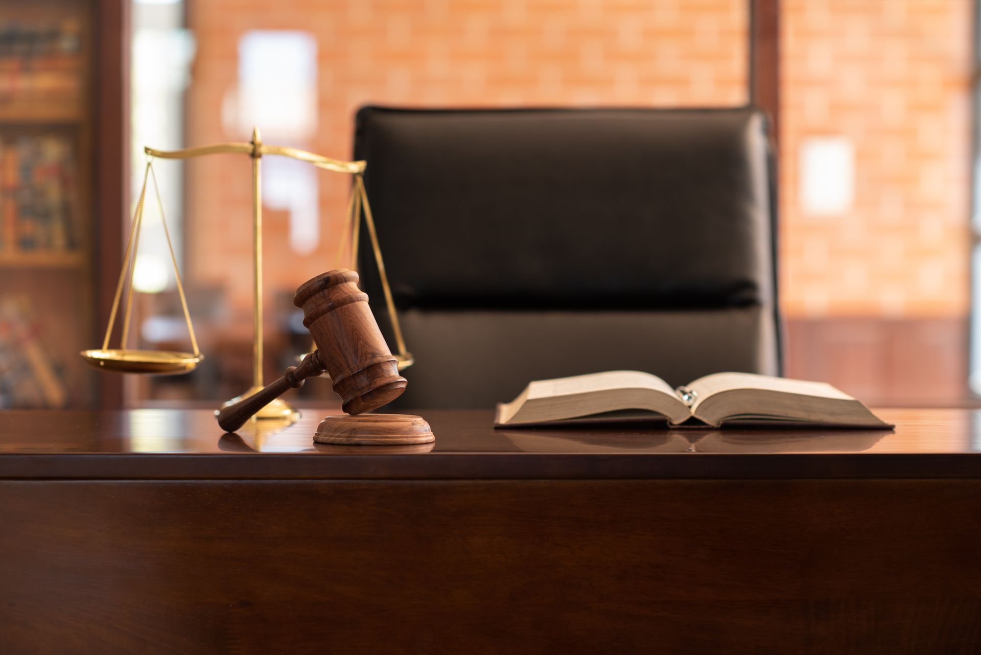 Marteau et balance d'un juge sur un bureau en bois, un livre ouvert dans un cabinet d'avocats.