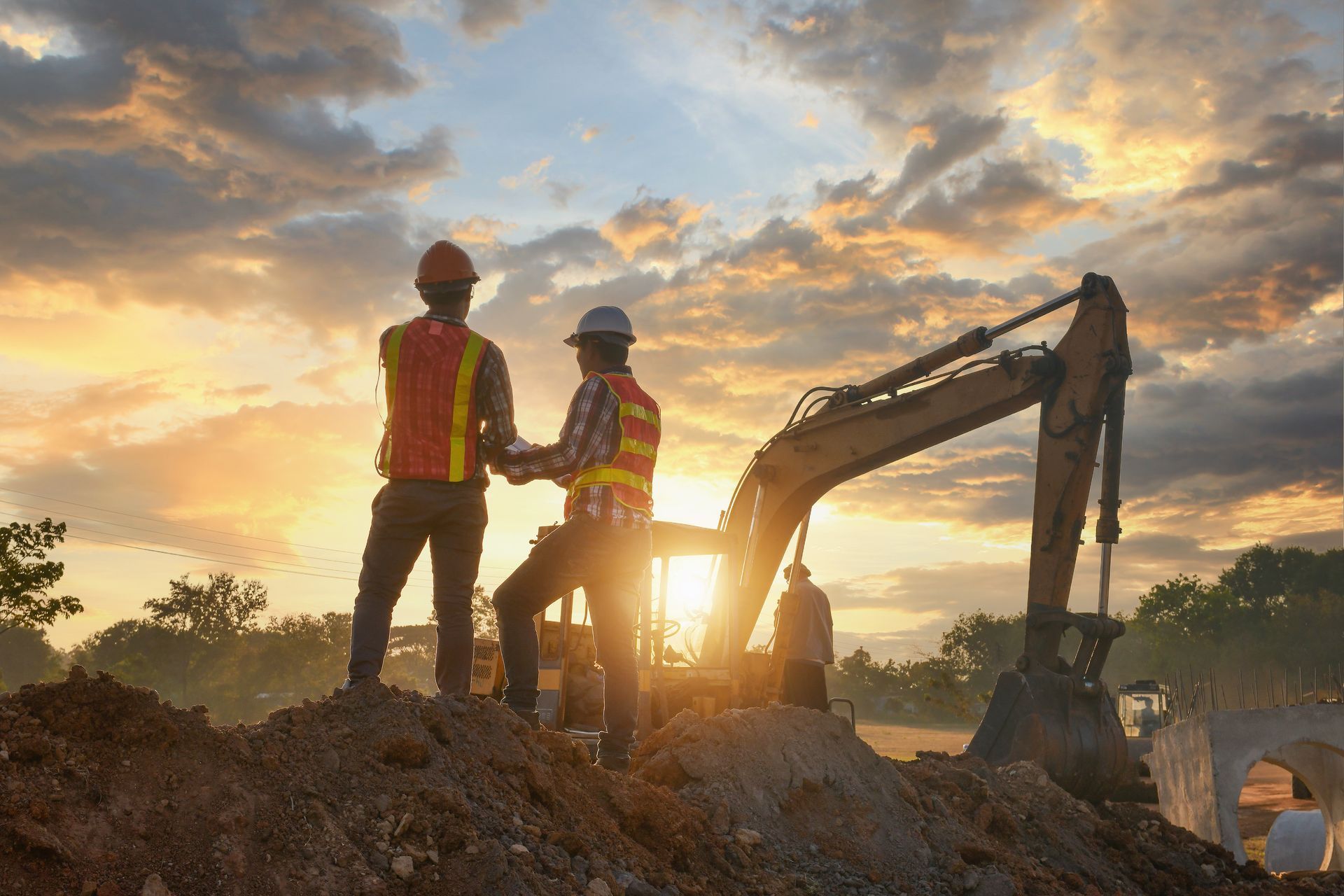 Des ouvriers du bâtiment avec une excavatrice au coucher du soleil.