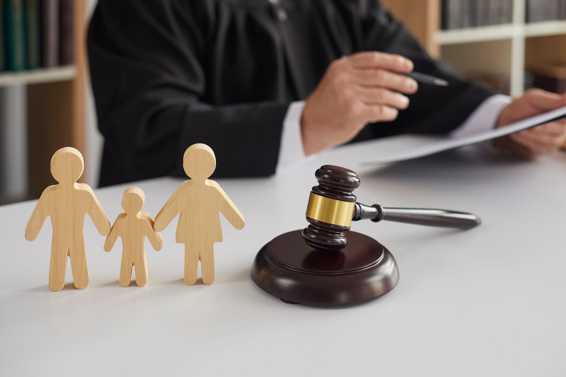Figurines familiales à côté du marteau d'un juge dans un contexte de garde d'enfants légal.