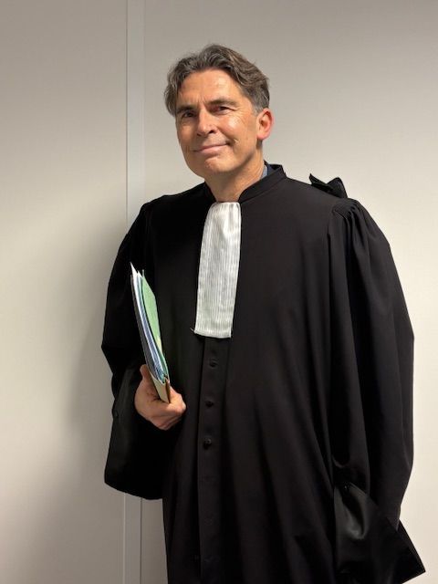 Maître Jean-Louis Colomb en robe noire, tenant des dossiers.