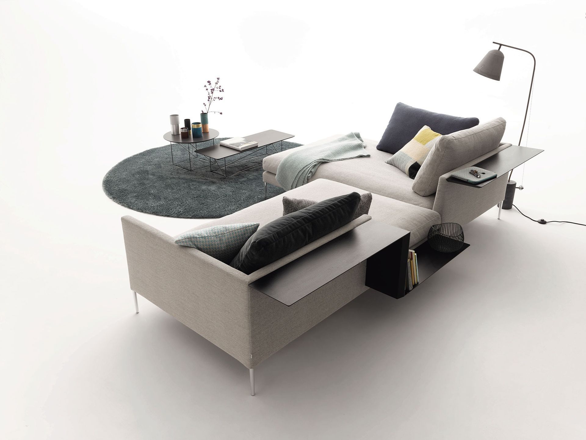 Modernes graues Modulsofa mit Hockern, rundem Teppich und minimalistischer Stehlampe in einem hellen Studio-Ambiente