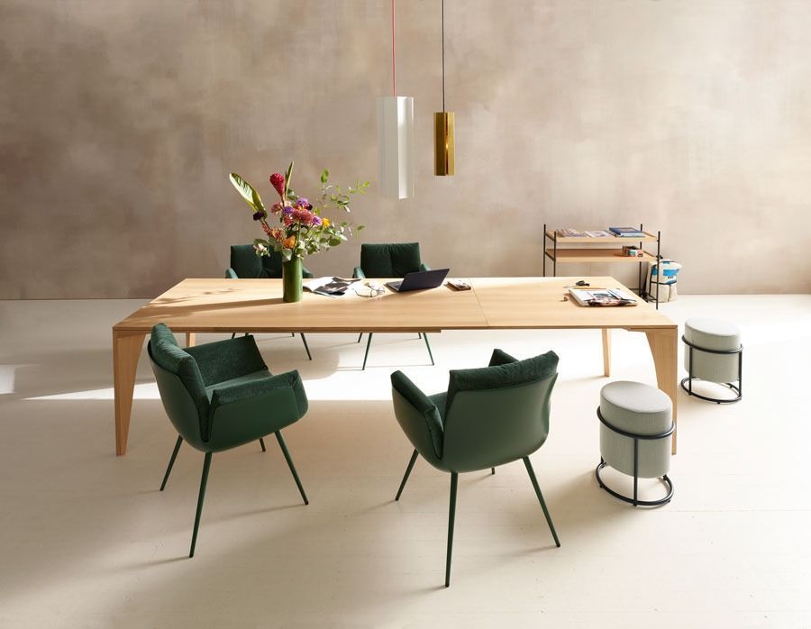 Modernes Esszimmer mit Holztisch, grünen Stühlen, Blumenvase und minimalistischer Einrichtung