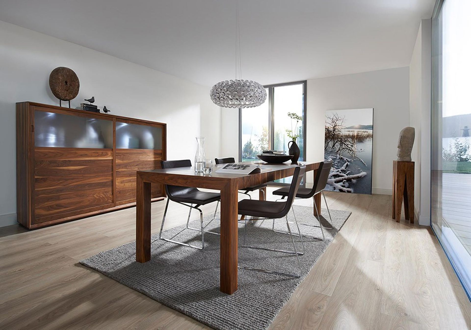 Modernes Esszimmer mit Holztisch, Stühlen, Anrichte, Teppich und großen Fenstern mit sanftem Licht